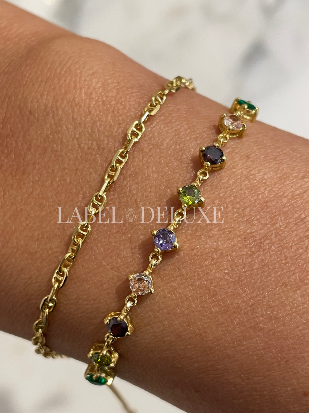 Fijne gouden armband met gekleurde zirkonia steentjes ( paars, groen, champagne ) om de pols - Label Deluxe