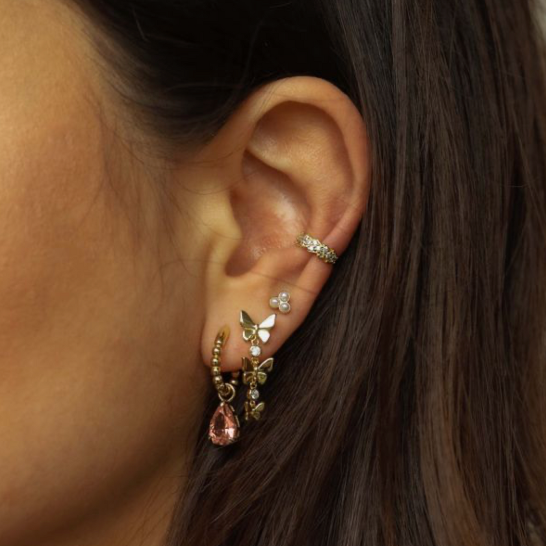Model draagt Karma Jewelry gouden vlinder oorbel close-up detail